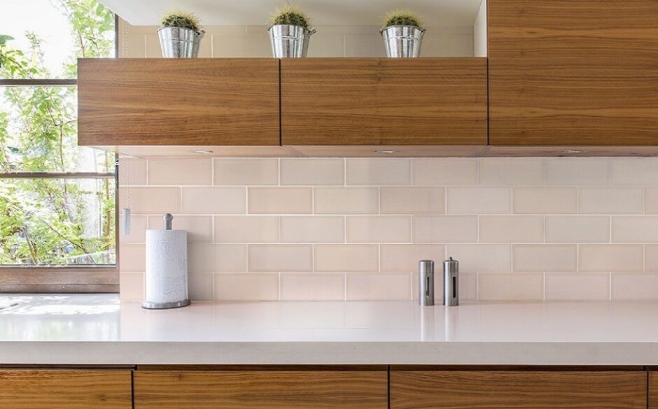 A kitchen with wooden cupboards and light pink metro tiles
