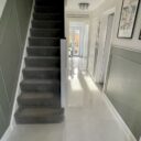 Hallway with dark grey staircase on the left and Scambio White marble effect floor tiles