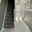 Hallway with dark grey staircase on the left and Scambio White marble effect floor tiles