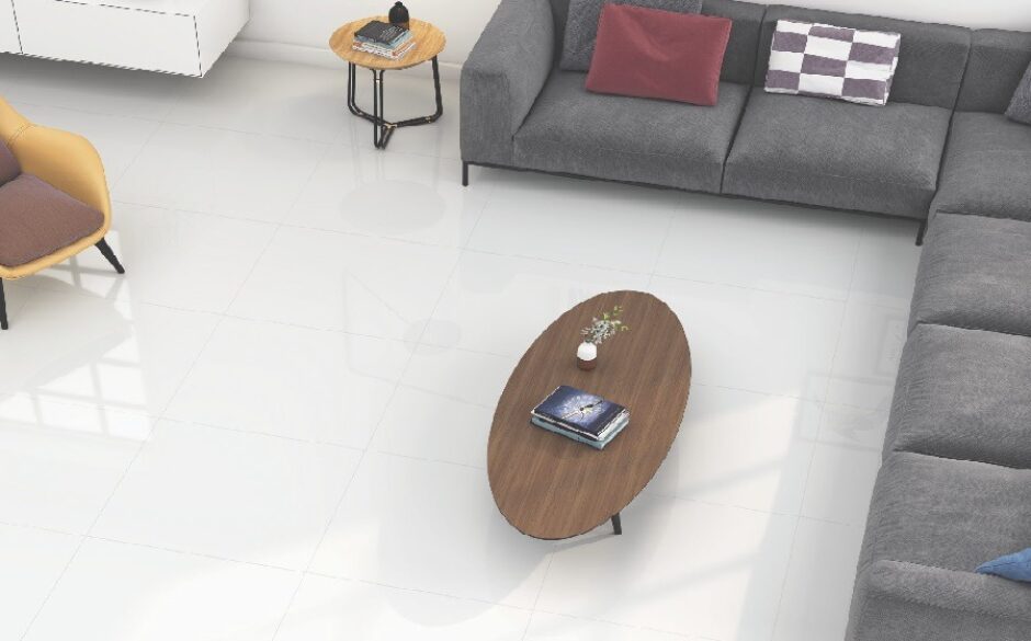 Living room setting with white marble effect tiles. An oval coffee table and an l shaped grey sofa complete the look.