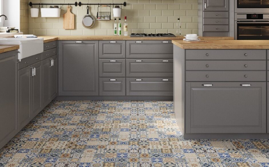 A kitchen with ivory metro tiles on the walls and patterned moroccan tiles on the floor. Grey cabinets and a kitchen island.