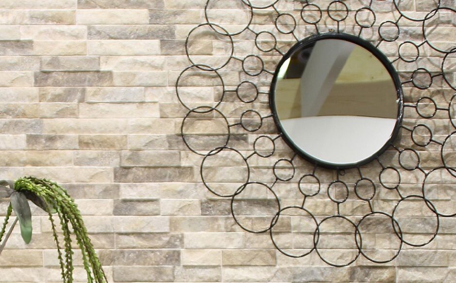 Close up of a mirror made up of lots of circles against a split face tiled wall