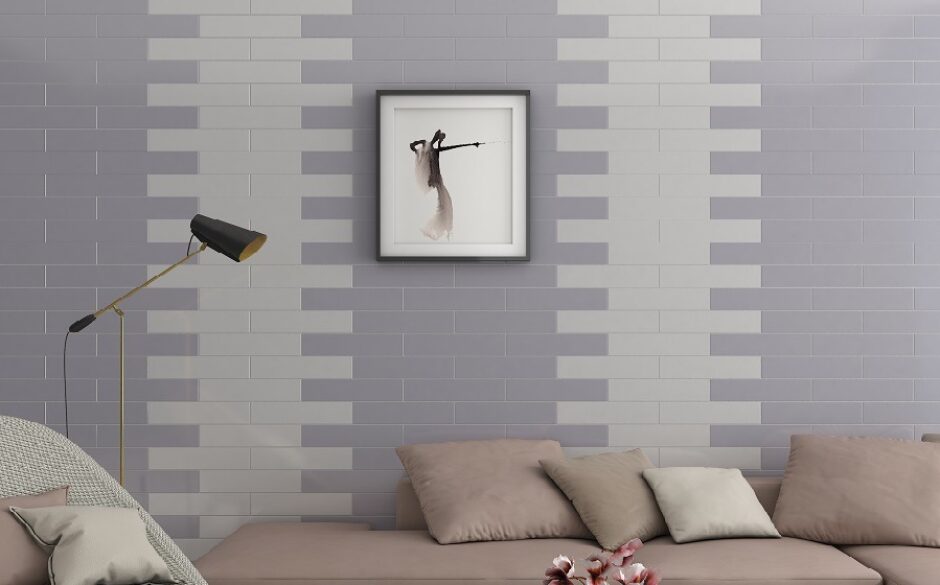 A living room with a sofa and square artwork. On the wall are grey and white metro tiles arranged in a geometric striped fashion.