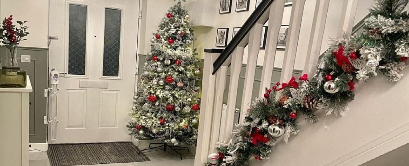 Landscape photo of a hallway with Scambio White floor tiles, a Christmas Tree in the back corner and a staircase on the right