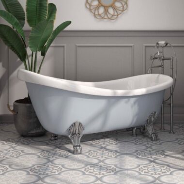 Close up of a large grey bath tub and chelsea victorian patterned floor tiles. A large green plant in a grey pot and half cropped gold mirror with oval gold embellishments