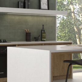 Photo of a kitchen breakfast bar with sage green ripple effect wall tiles behind the counter