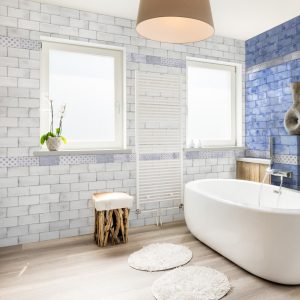 Vita White Flat Metros on a bathroom wall. A light airy room with a feature blue wall to the right.