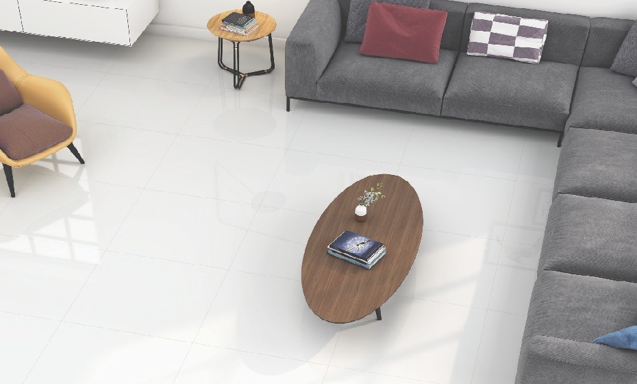 Living room setting with white marble effect tiles. An oval coffee table and an l shaped grey sofa complete the look.